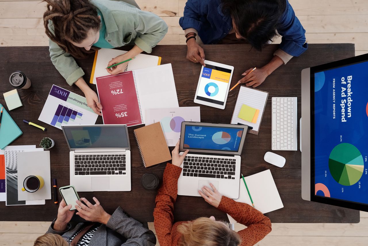 Une équipe variée travaille ensemble sur des stratégies de marketing digital autour d’une table, avec des ordinateurs portables et des tablettes.